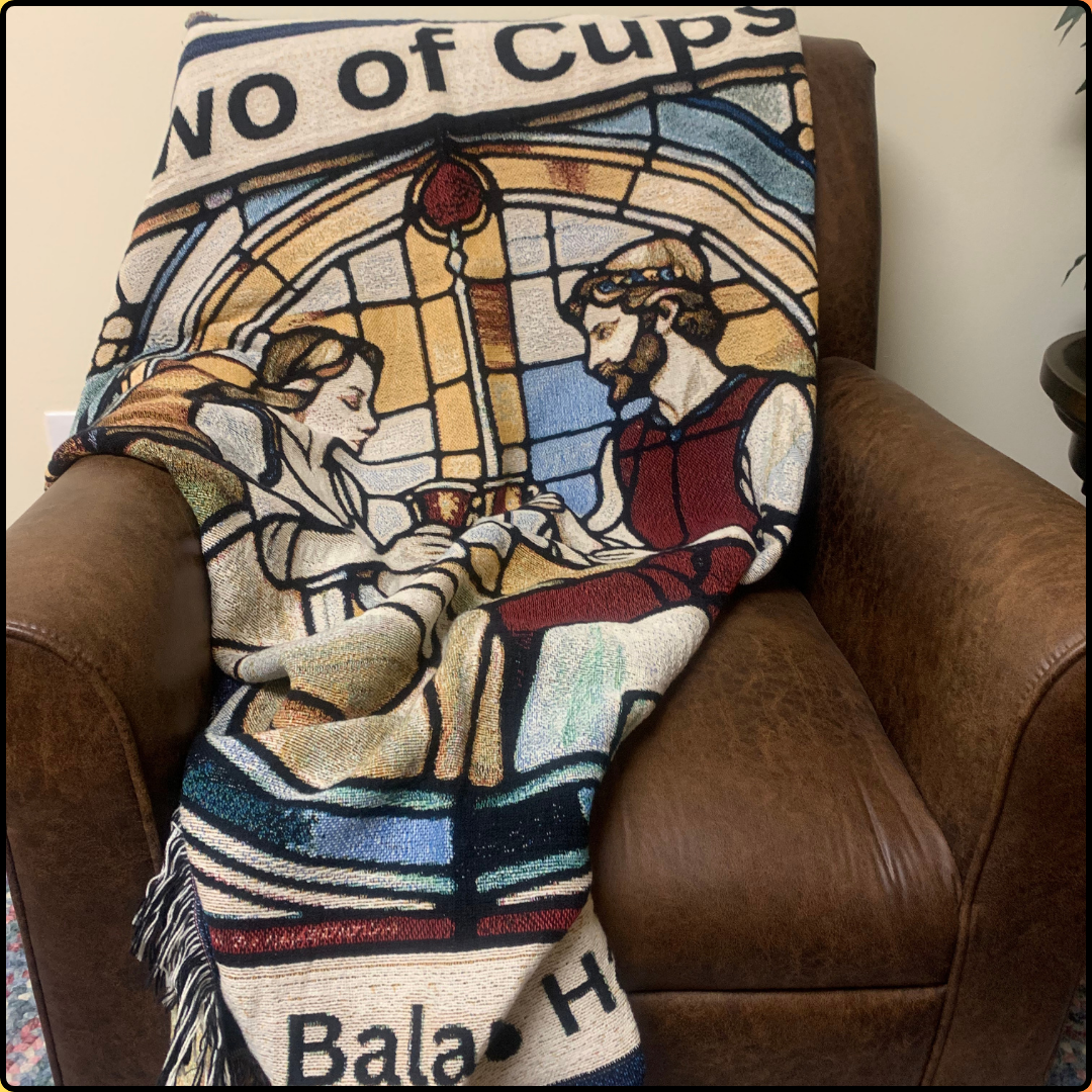 Two of Cups Heirloom Blanket Mister Obtuse mugs and stuff draped over brown leather chair front view